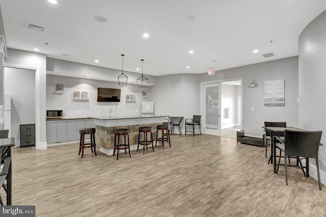 kitchen with stainless steel microwave, light wood-type flooring, and visible vents