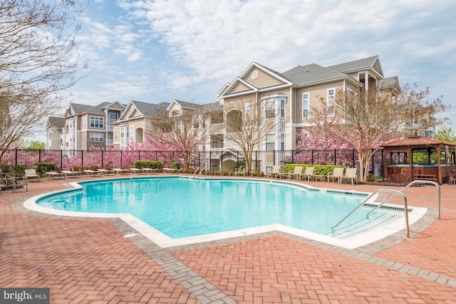 community pool featuring a gazebo, a patio, fence, and a residential view