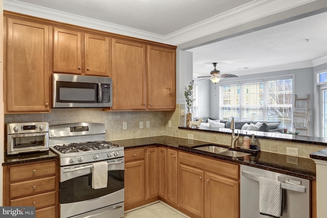 kitchen featuring tasteful backsplash, dark stone countertops, stainless steel appliances, crown molding, and a sink