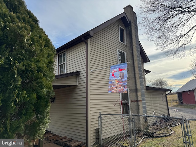 view of side of home featuring a chimney and fence