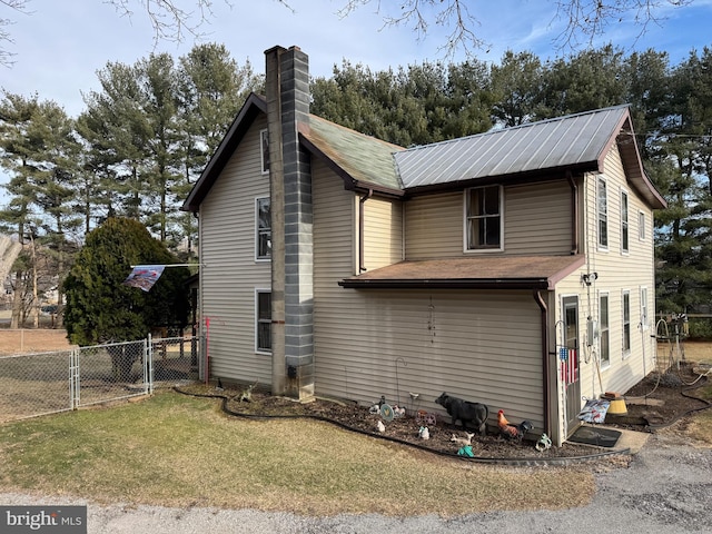 view of side of home with a yard, a chimney, and fence