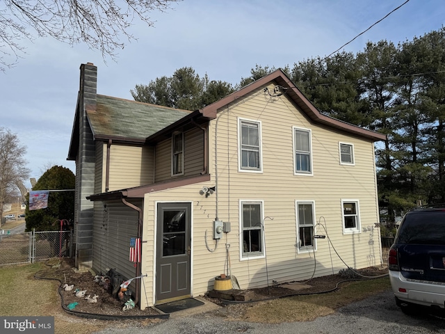 back of property with a chimney and fence