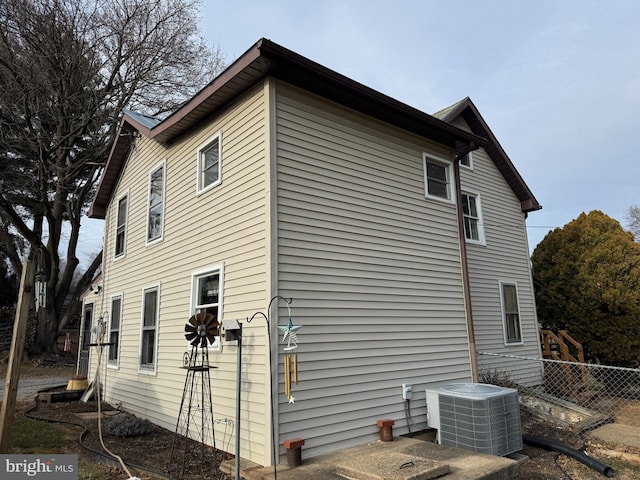 view of side of home with central AC and fence