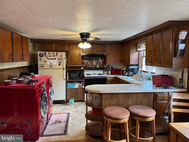 kitchen with light countertops, freestanding refrigerator, black microwave, independent washer and dryer, and a peninsula