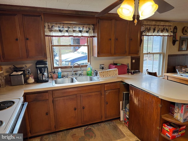 kitchen featuring brown cabinets, light countertops, a sink, and hanging light fixtures