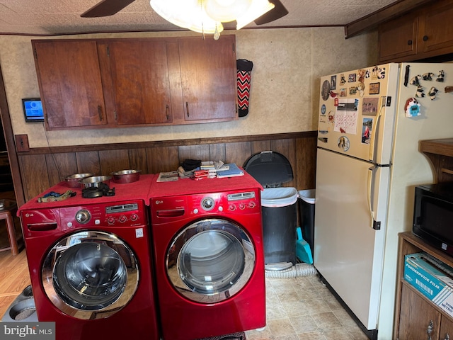 laundry area featuring laundry area, wooden walls, a wainscoted wall, ceiling fan, and washing machine and dryer