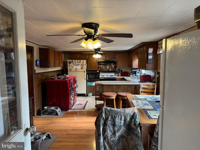 kitchen with black microwave, washing machine and dryer, a peninsula, range with electric stovetop, and freestanding refrigerator