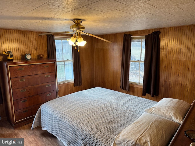 bedroom featuring wood walls, dark wood-style flooring, and a ceiling fan