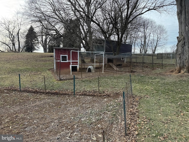 view of yard featuring an outbuilding, a rural view, fence, and exterior structure