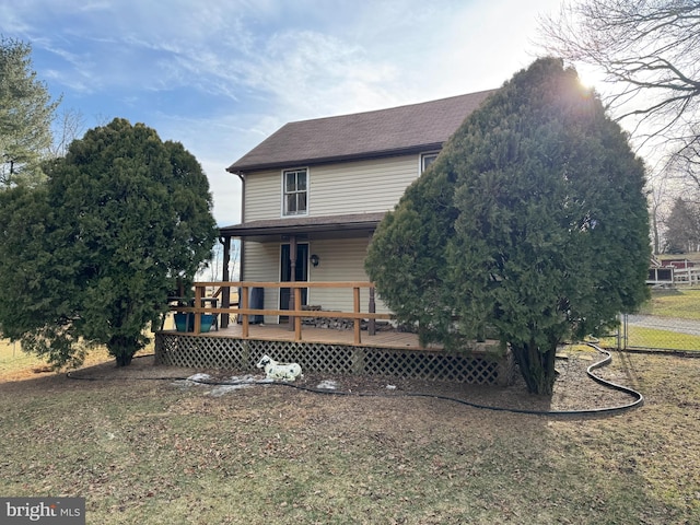 rear view of property with a shingled roof, a lawn, and a wooden deck