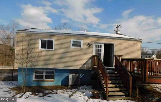 snow covered property featuring cooling unit and a wooden deck