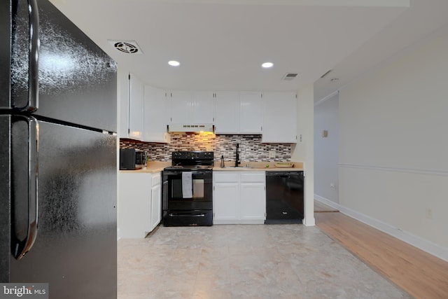 kitchen featuring visible vents, light countertops, white cabinetry, under cabinet range hood, and black appliances