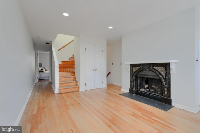 unfurnished living room with stairs, baseboards, and wood finished floors