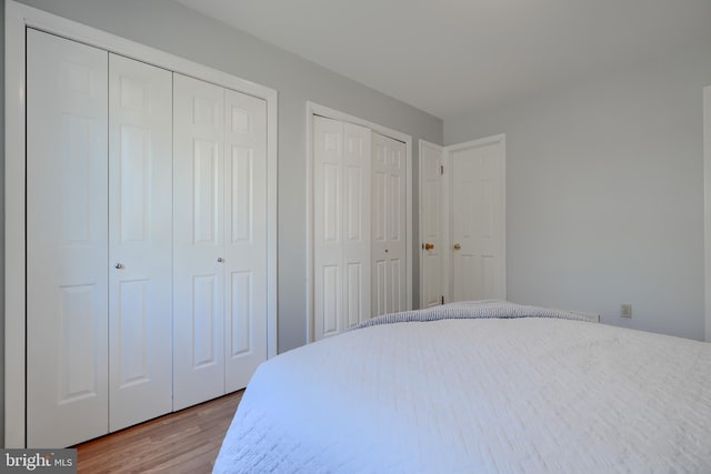 bedroom with multiple closets and wood finished floors