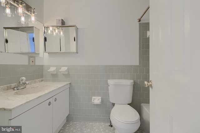 bathroom featuring toilet, walk in shower, tile walls, and vanity