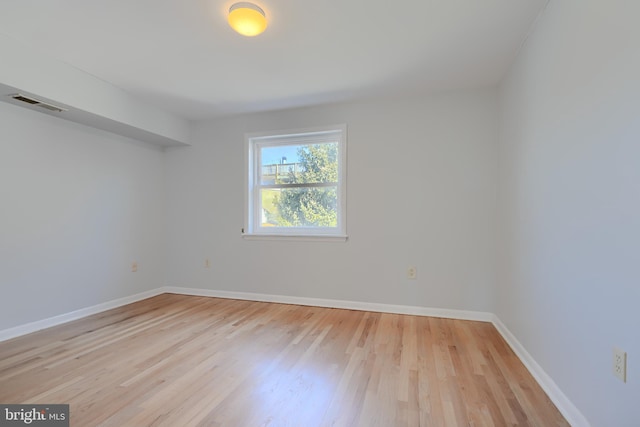 empty room featuring light wood-type flooring, visible vents, and baseboards