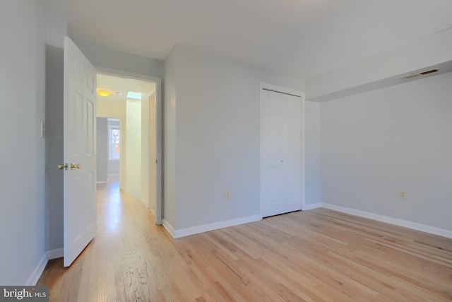 spare room with light wood-style flooring, visible vents, and baseboards