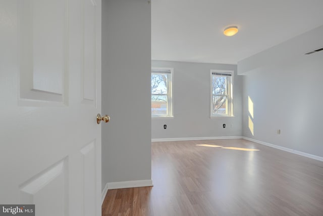 unfurnished room featuring visible vents, baseboards, and wood finished floors