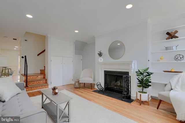 living room with a fireplace with flush hearth, stairs, wood finished floors, and recessed lighting