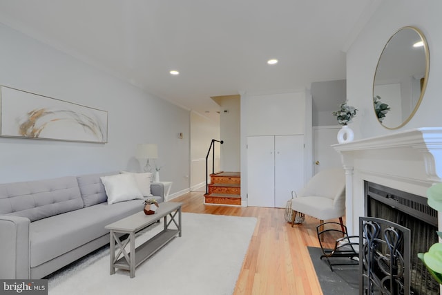 living area featuring recessed lighting, a fireplace, stairway, and wood finished floors