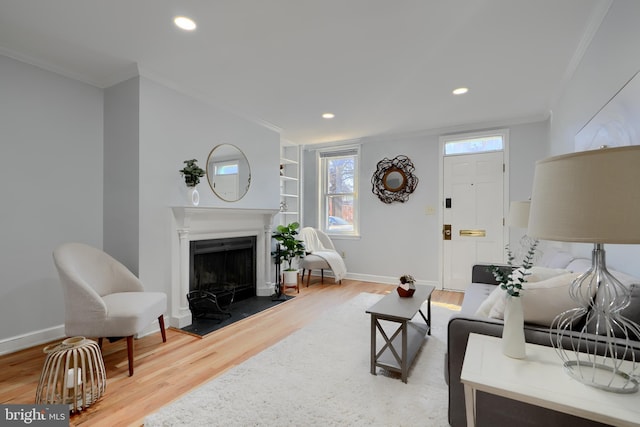 living room with a fireplace, baseboards, crown molding, and wood finished floors