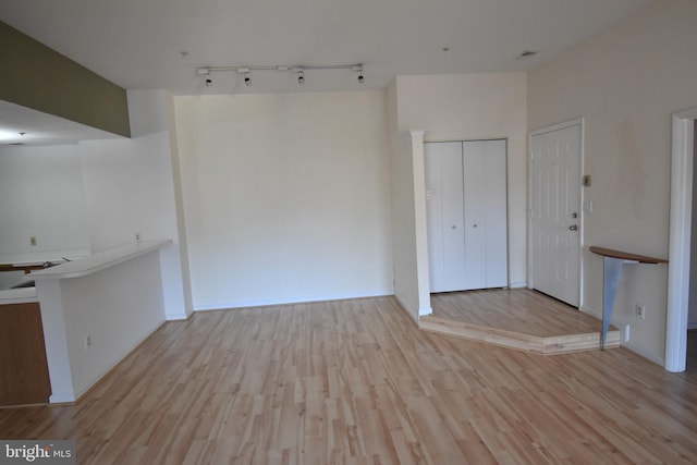 interior space featuring baseboards, rail lighting, and light wood-style floors