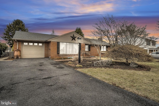 ranch-style home with a garage, a shingled roof, aphalt driveway, and brick siding