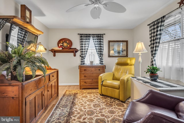 sitting room with baseboards, ceiling fan, and light wood finished floors