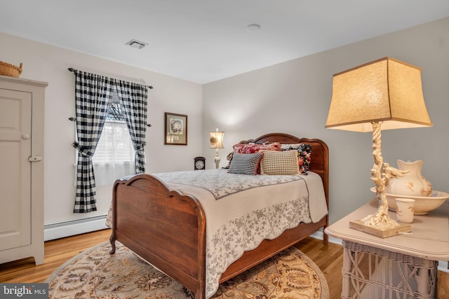 bedroom featuring a baseboard radiator, visible vents, and light wood-style floors