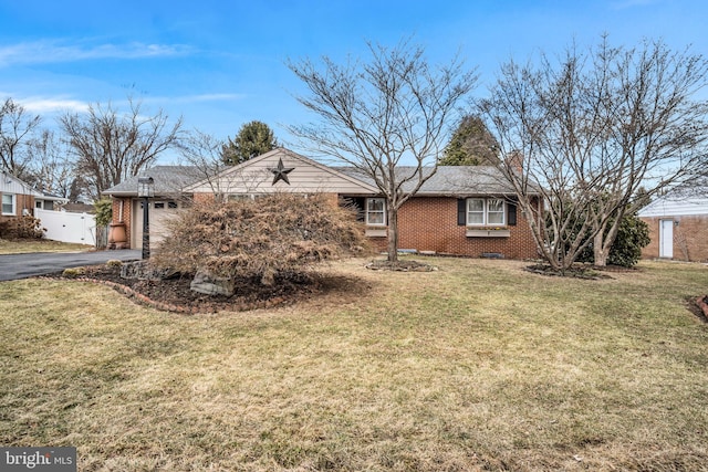 ranch-style house with brick siding, an attached garage, fence, driveway, and a front lawn