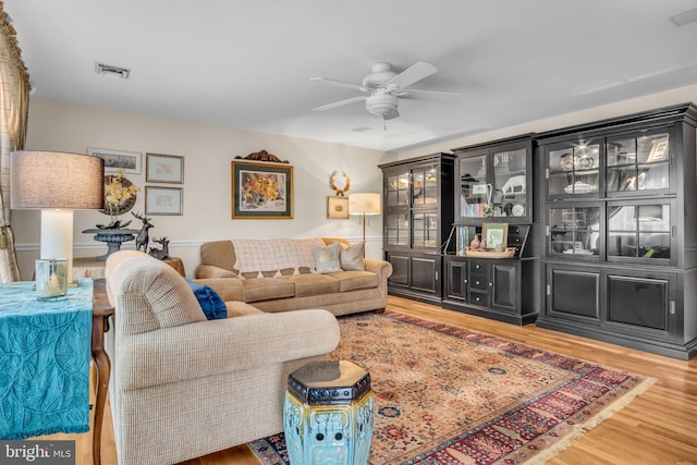 living room featuring a ceiling fan, visible vents, and wood finished floors