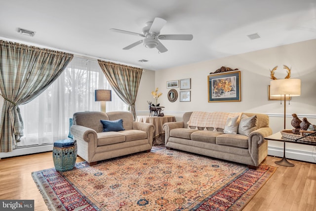 living room with ceiling fan, a baseboard radiator, wood finished floors, and visible vents