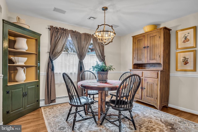 dining area featuring a chandelier, a baseboard radiator, visible vents, baseboards, and light wood-style floors