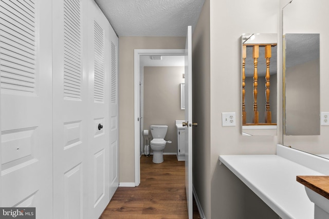 bathroom featuring vanity, wood finished floors, a closet, a textured ceiling, and toilet