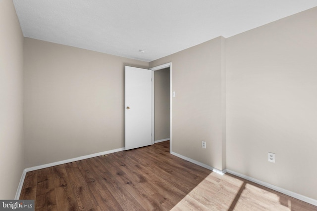 spare room with baseboards and wood finished floors