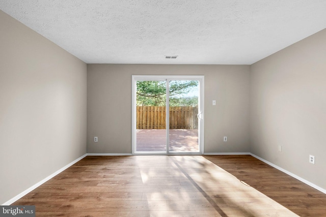 unfurnished room featuring a textured ceiling, baseboards, and wood finished floors