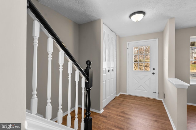 entrance foyer with stairs, wood finished floors, baseboards, and a textured ceiling