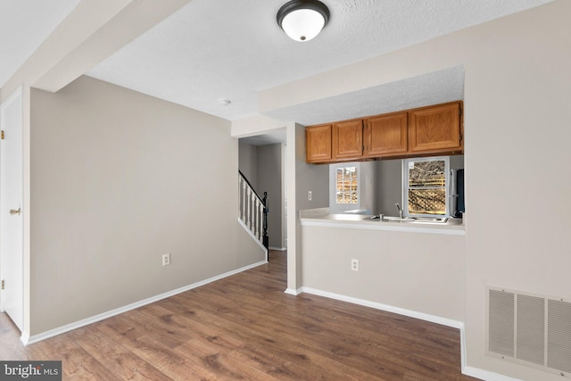 kitchen with visible vents, baseboards, brown cabinets, wood finished floors, and a textured ceiling