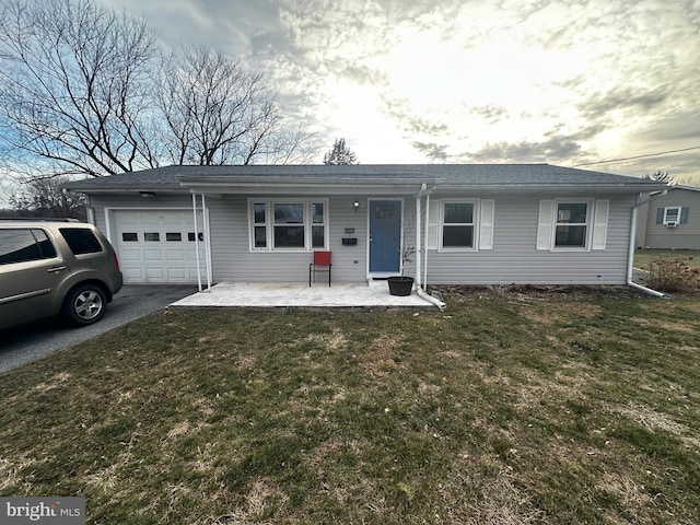 ranch-style home with driveway, covered porch, an attached garage, and a front lawn