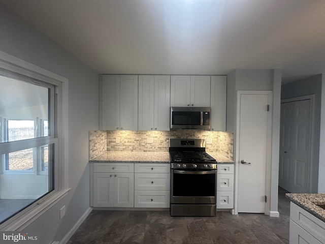 kitchen featuring light stone countertops, tasteful backsplash, appliances with stainless steel finishes, and white cabinets