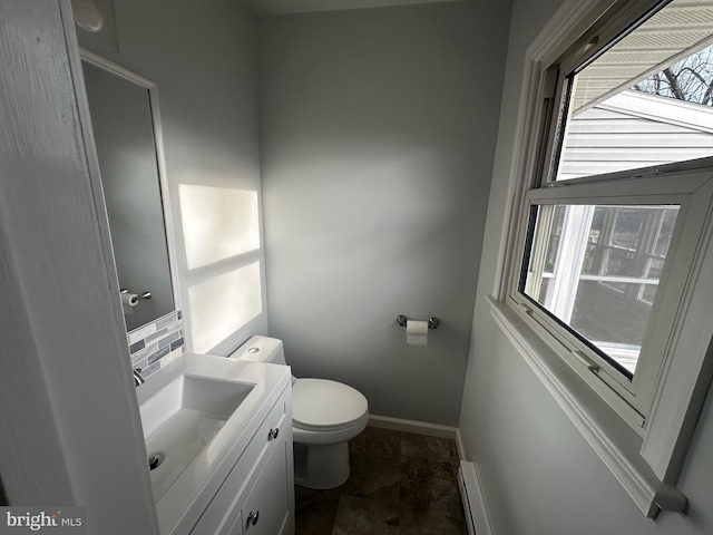 half bathroom with baseboards, vanity, and toilet