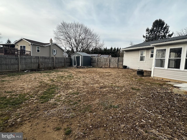 view of yard with a fenced backyard, a storage unit, and an outbuilding