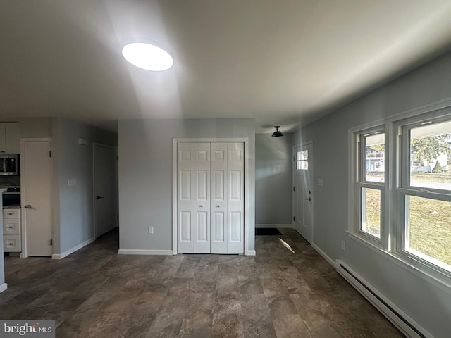 unfurnished bedroom featuring baseboards, a baseboard heating unit, and multiple closets