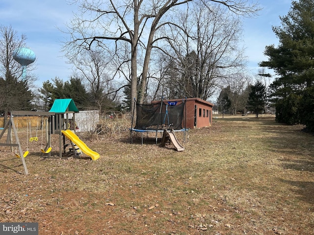 view of yard with a trampoline, an outbuilding, and a playground