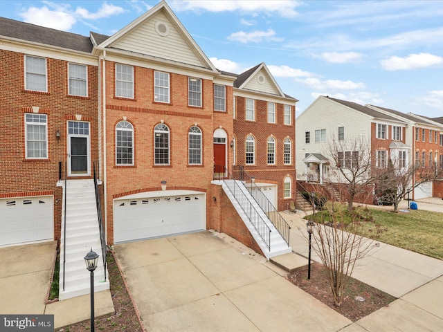 multi unit property featuring stairs, brick siding, concrete driveway, and an attached garage