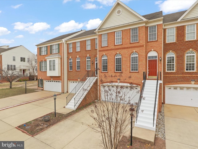 multi unit property featuring concrete driveway, brick siding, and a garage