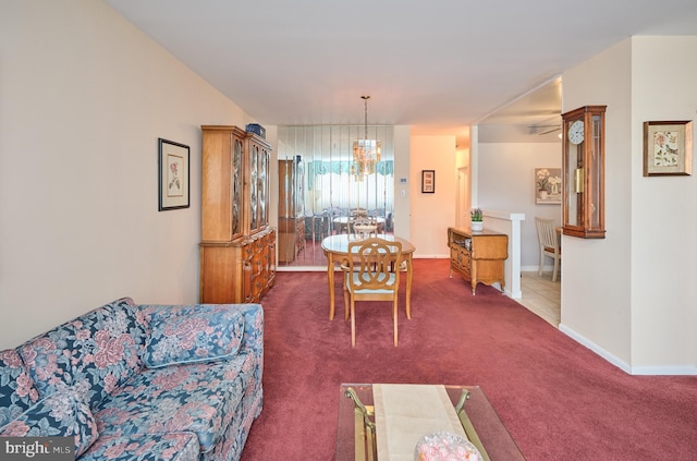 dining area with a chandelier, dark carpet, and baseboards