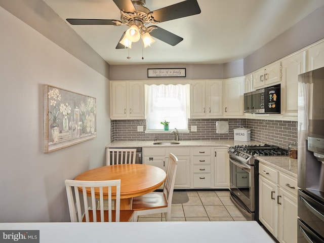 kitchen with light tile patterned floors, a sink, white cabinetry, appliances with stainless steel finishes, and tasteful backsplash