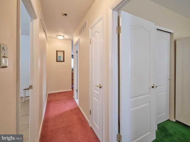 hallway with carpet flooring, visible vents, and baseboards