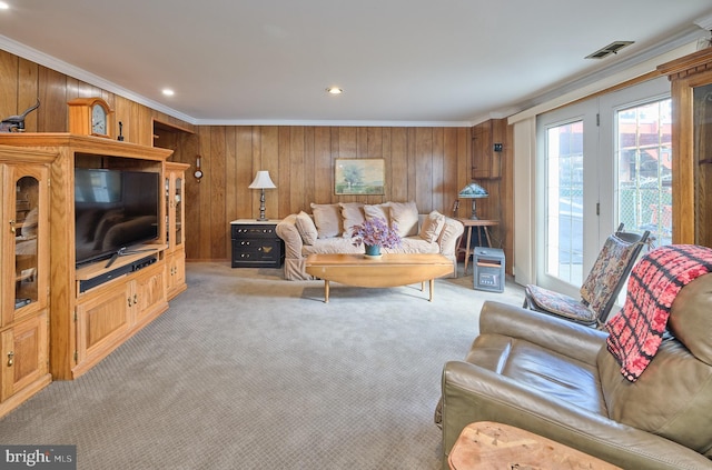 living room with light carpet, wood walls, visible vents, and crown molding